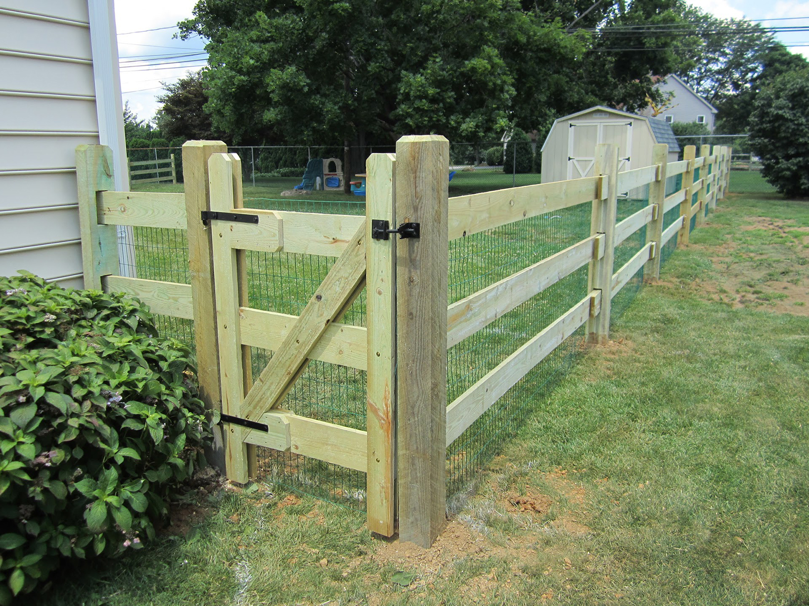 slip rail fence with wire mesh in yard with gate