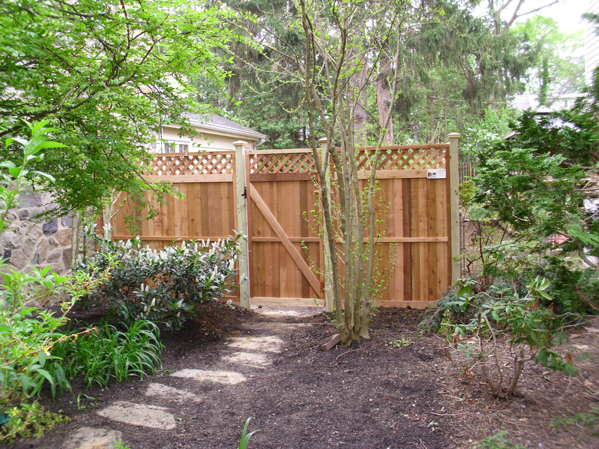 Framed wood privacy fencing with lattice in back yard with gate