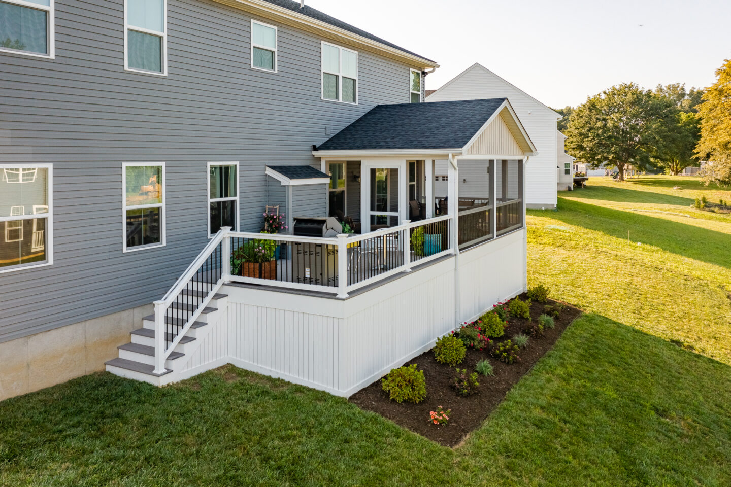 image of a timbertech deck with screenind in roof area white vynl railing with black aluminum balusters and vynl deck skirting to creat and underdeck storage area built by integrous fences and decks