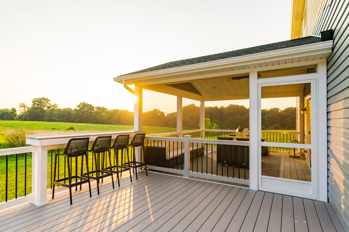 image of a deck with a screened in roof in avondale pa built by integrous fences and decks featuring a deck board bar timbertech decking and white vynl railing with black aluminum balusters