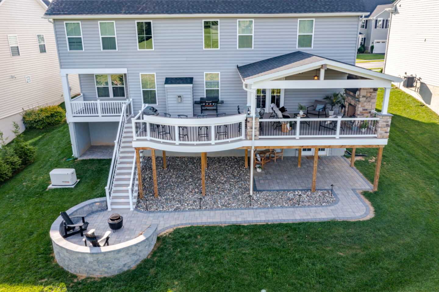 image of a deck in west bradford pa built by integrous fences and decks featuring a roof area a curved deck board bar timbertech decking and white vinyl railing with black aluminum balusters