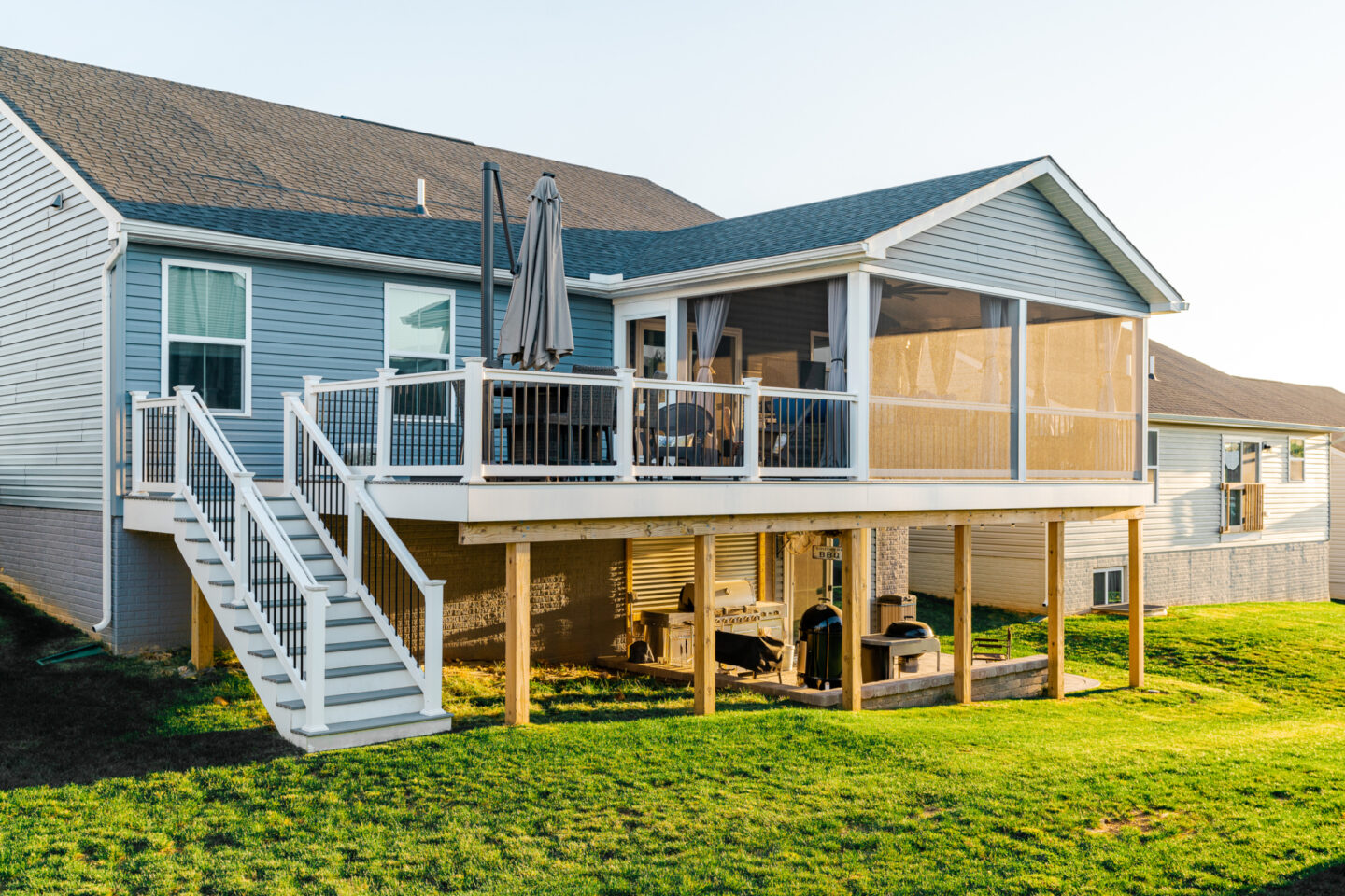 image of a deck with a screened in roof in coatesville pa built by integrous fences and decks featuring a screened in roof area an open deck timbertech decking white vinyl railing with black aluminum balusters and one set of stairs to grade