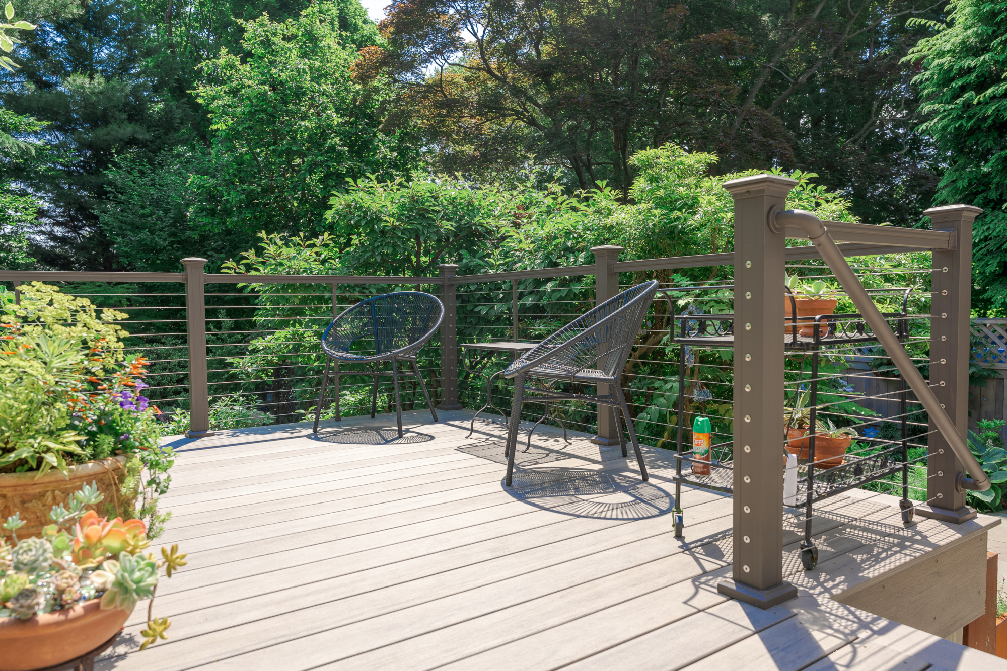 image of a deck in elkins pa built by integrous fences and decks featuring cable railing and timbertech decking located in a beautiful garden backyard