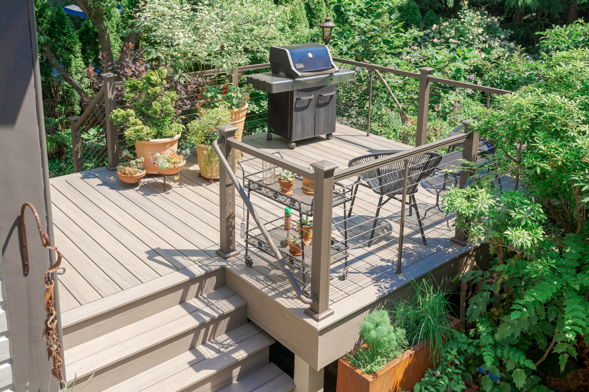 image of a deck in elkins pa built by integrous fences and decks featuring cable railing and timbertech decking located in a beautiful garden backyard