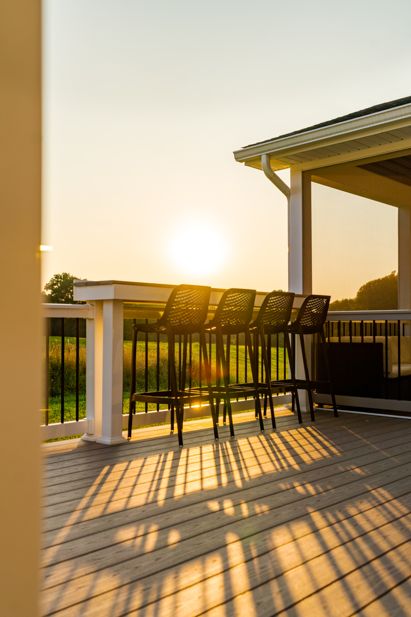 image of a deck with a screened in roof in avondale pa built by integrous fences and decks featuring a deck board bar timbertech decking and white vynl railing with black aluminum balusters