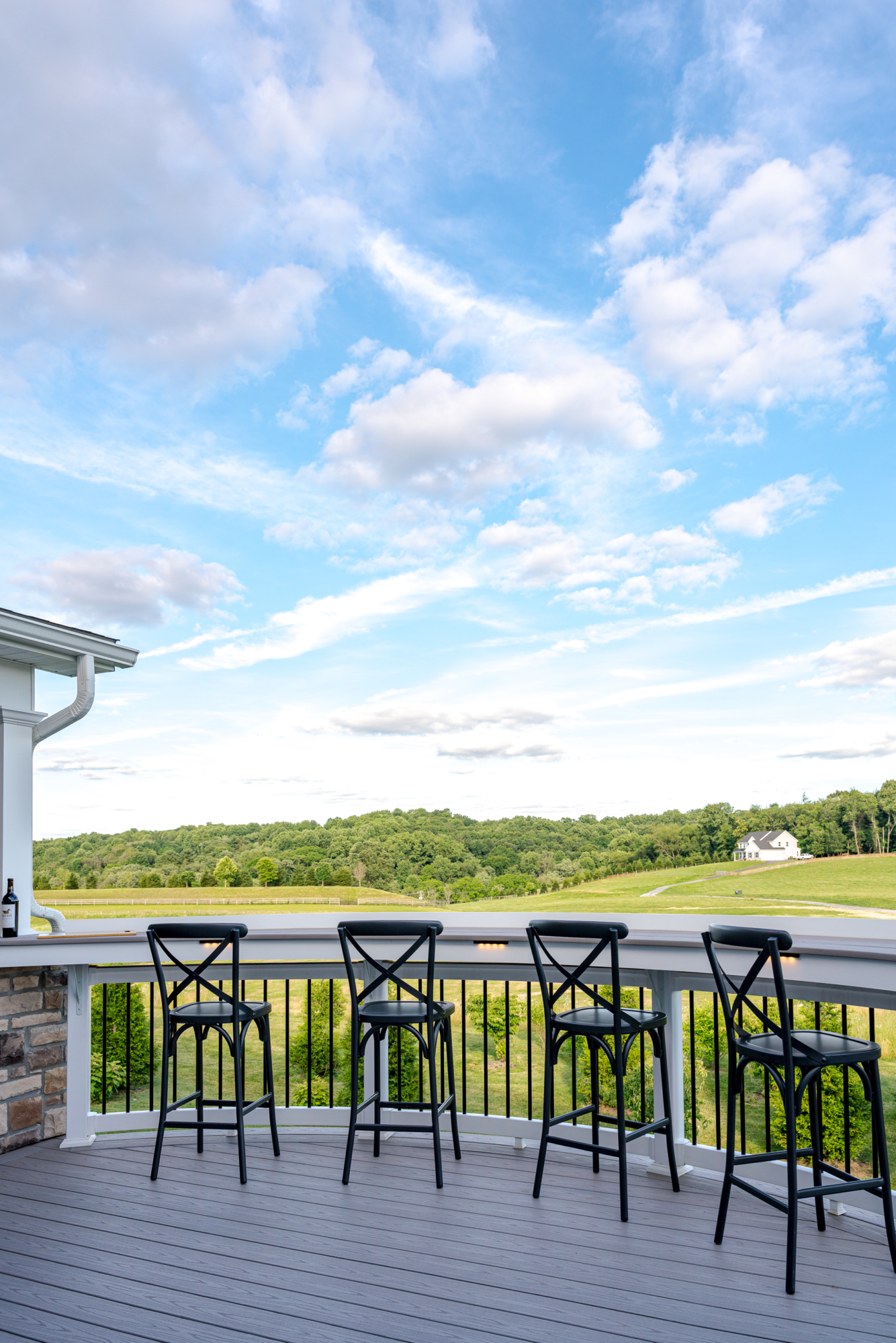 image of a deck in west bradford pa built by integrous fences and decks featuring a roof area a curved deck board bar timbertech decking and white vinyl railing with black aluminum balusters