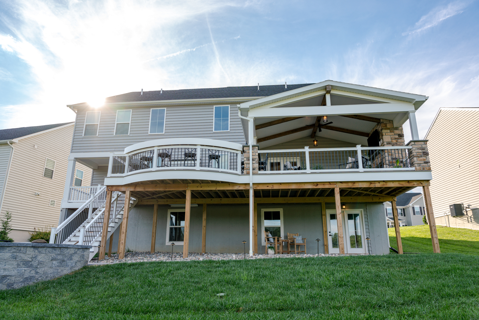 image of a deck in west bradford pa built by integrous fences and decks featuring a roof area a curved deck board bar timbertech decking and white vinyl railing with black aluminum balusters