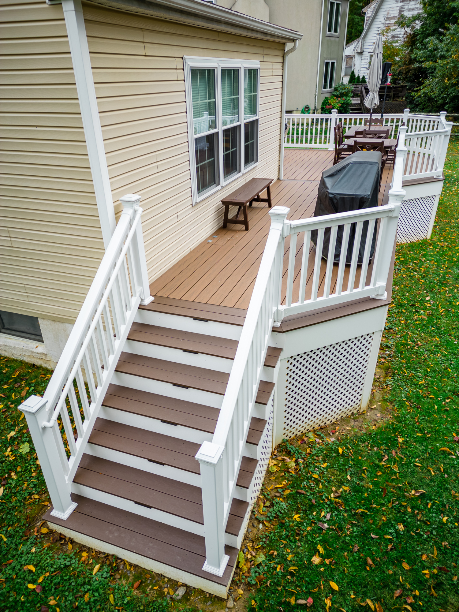 image of a deck with lattice skirting in media pa built by integrous fences and decks featuring timbertech decking white vinyl railing, and white vinyl underdeck lattice skirting with two steps to grade