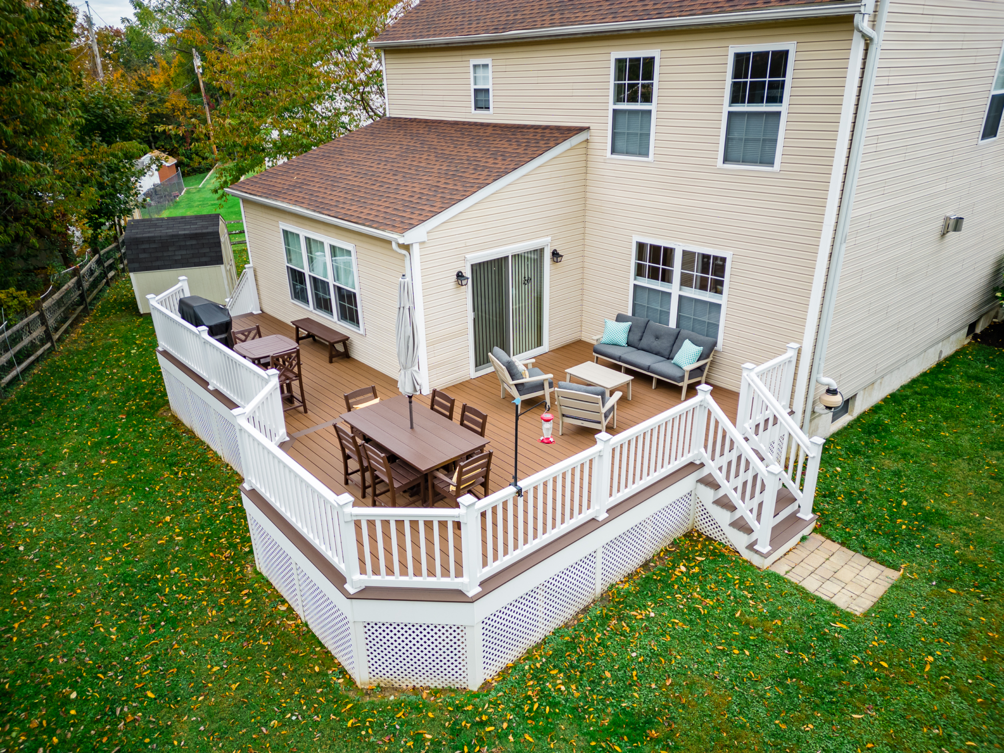 image of a deck with lattice skirting in media pa built by integrous fences and decks featuring timbertech decking white vinyl railing, and white vinyl underdeck lattice skirting with two steps to grade