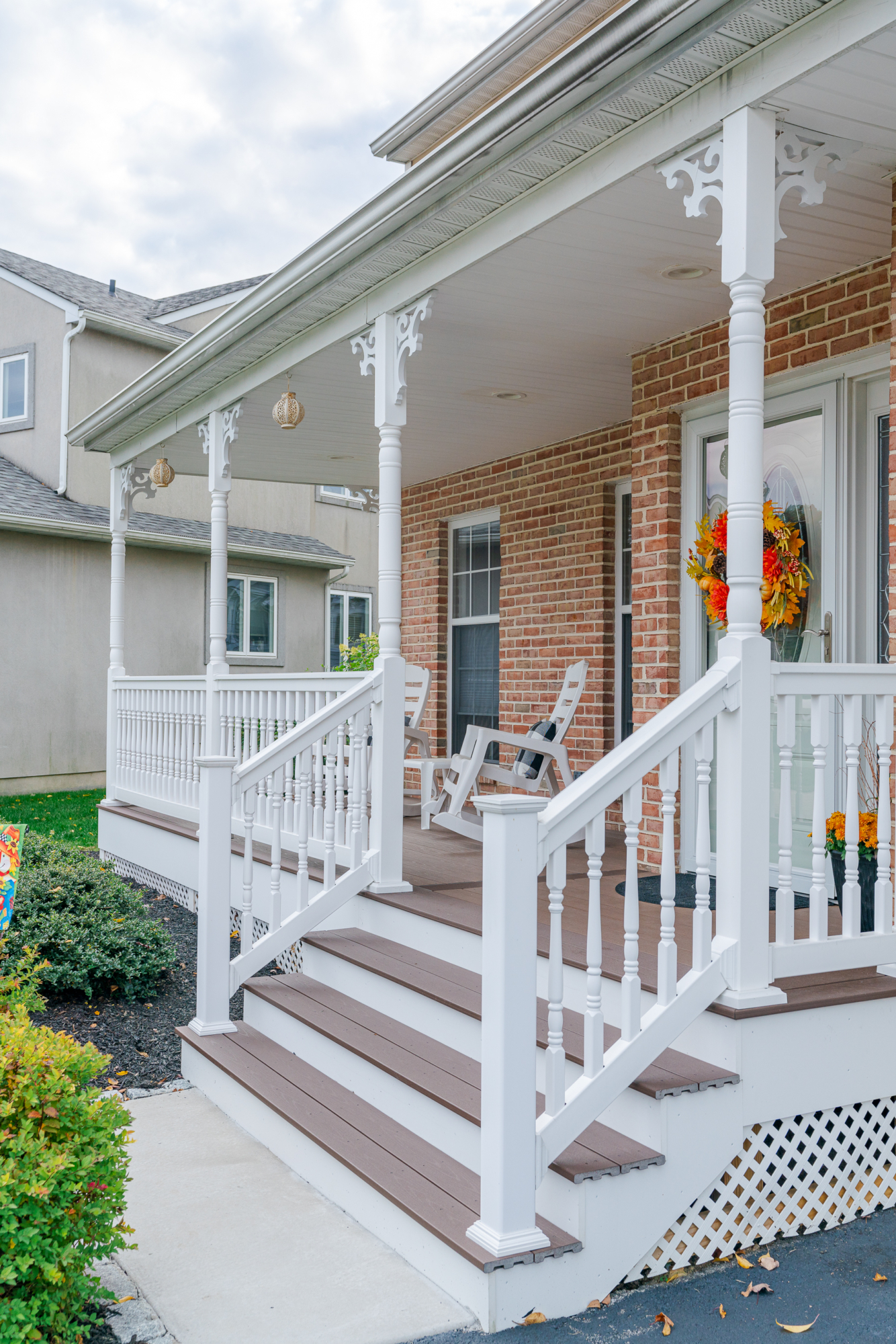 image of a porch with decorative details and lattice skirting in media pa built by integrous fences and decks featuring timbertech decking white vinyl railing and white vinyl with decorative spindles decorative white posts white decorative post to beam brackets and underdeck lattice skirting