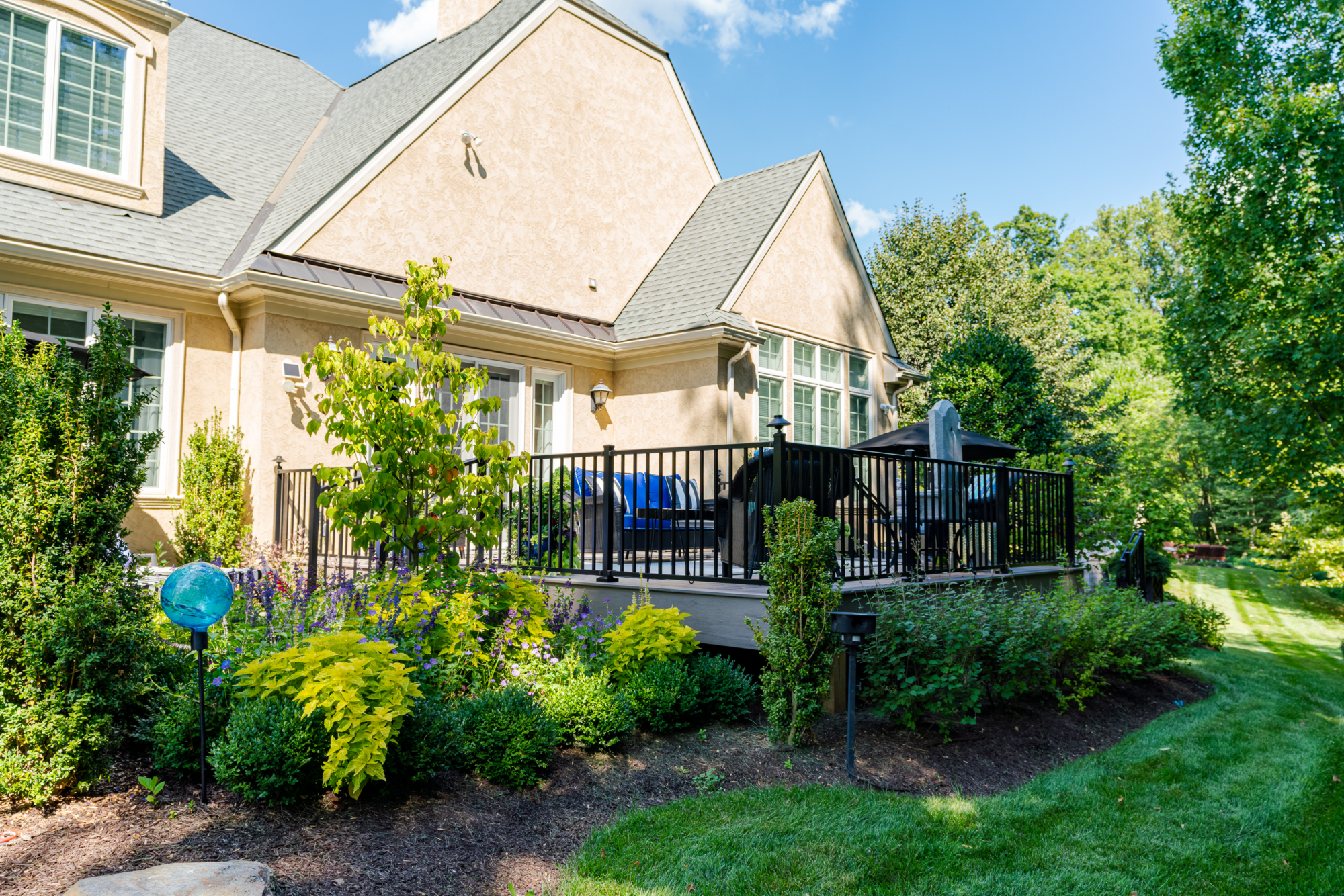 image of a timbertech deck with westbury railing built by integrous fences and decks surrounded by beautiful landscaping