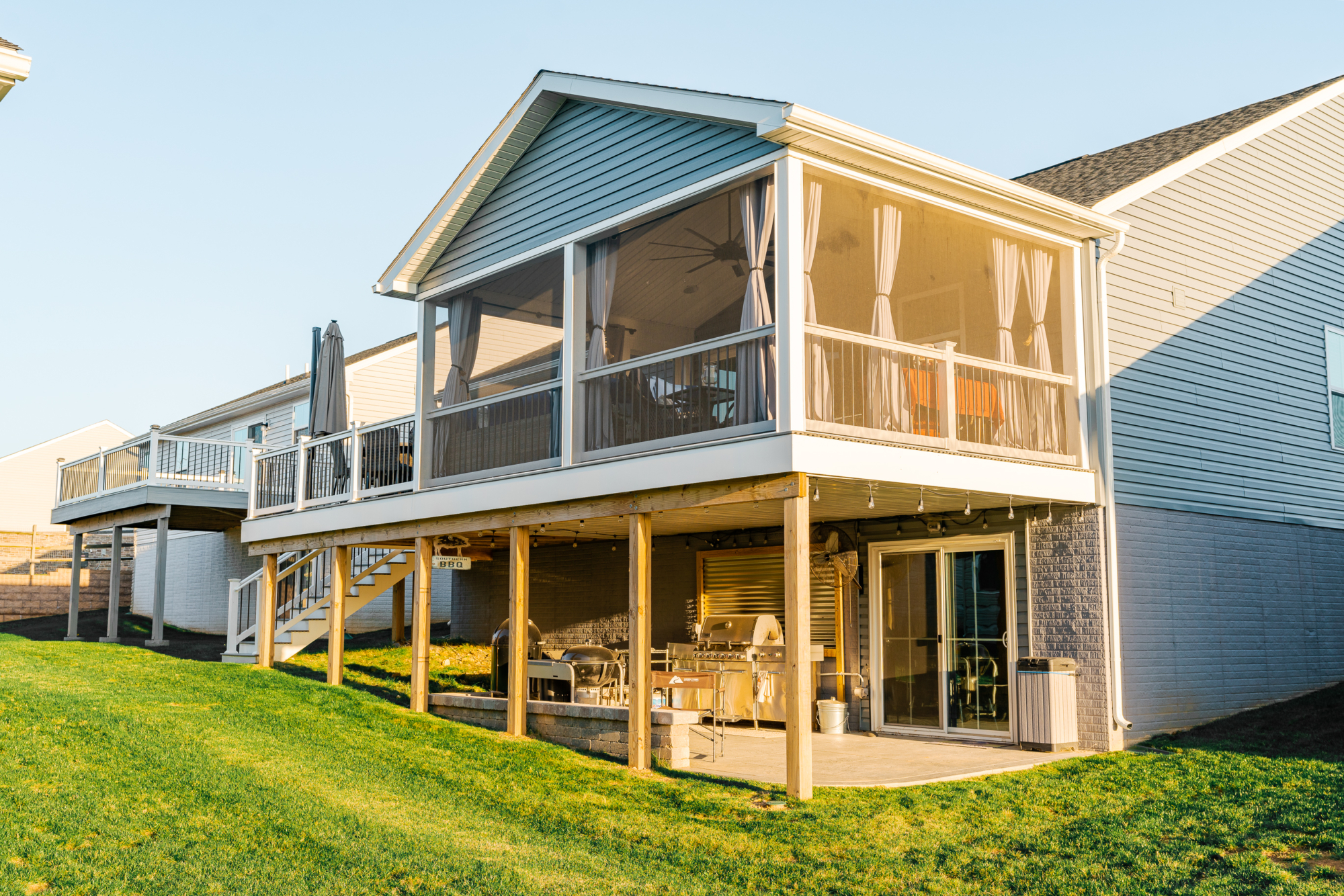 image of a deck with a screened in roof in coatesville pa built by integrous fences and decks featuring a screened in roof area an open deck timbertech decking white vinyl railing with black aluminum balusters and one set of stairs to grade