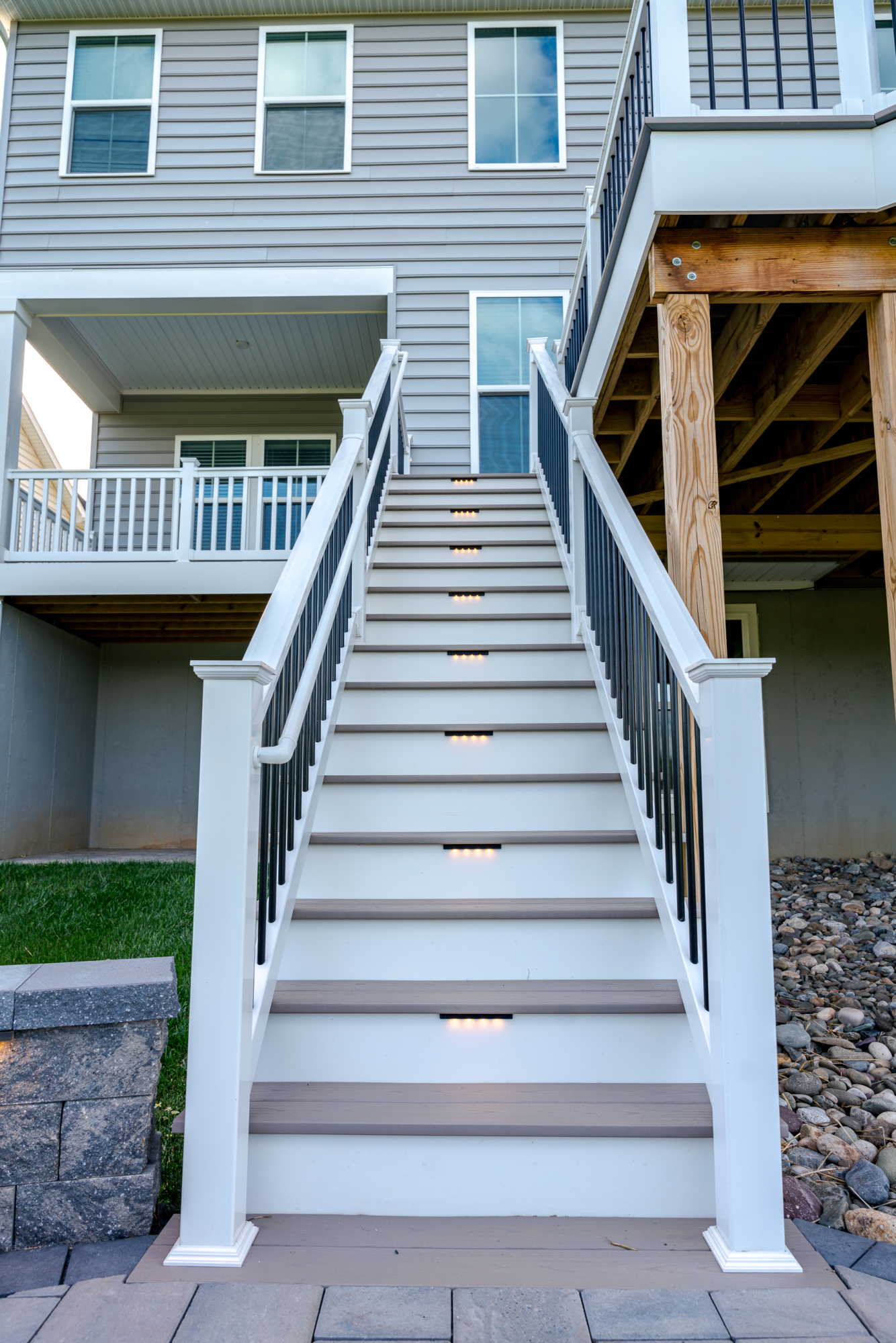 image of a deck in west bradford pa built by integrous fences and decks featuring a roof area a curved deck board bar timbertech decking and white vinyl railing with black aluminum balusters