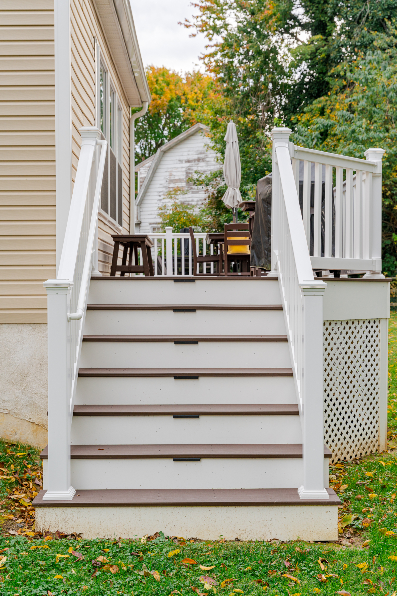 image of a deck with lattice skirting in media pa built by integrous fences and decks featuring timbertech decking white vinyl railing, and white vinyl underdeck lattice skirting with two steps to grade