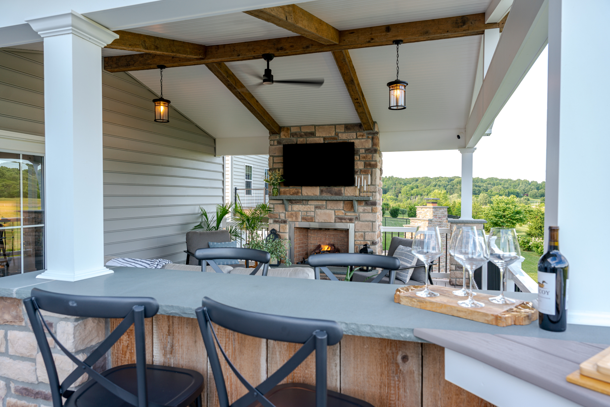 image of a deck in west bradford pa built by integrous fences and decks featuring a roof area a curved deck board bar timbertech decking and white vinyl railing with black aluminum balusters