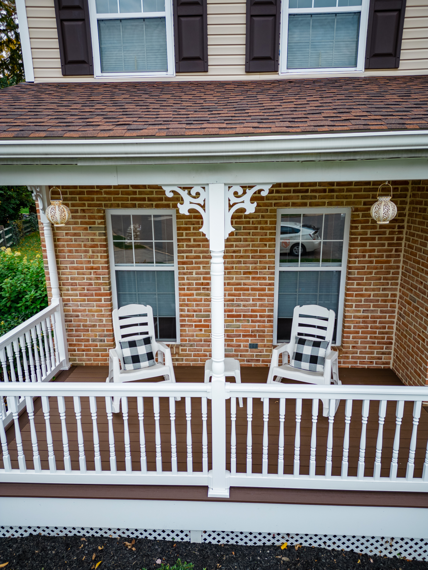 image of a porch with decorative details and lattice skirting in media pa built by integrous fences and decks featuring timbertech decking white vinyl railing and white vinyl with decorative spindles decorative white posts white decorative post to beam brackets and underdeck lattice skirting