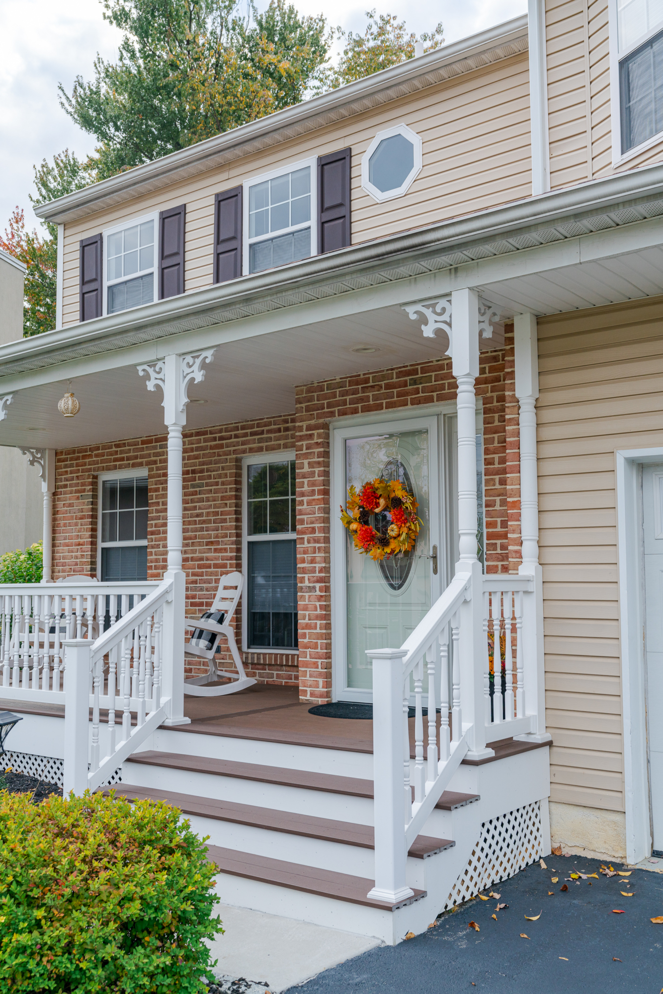image of a porch with decorative details and lattice skirting in media pa built by integrous fences and decks featuring timbertech decking white vinyl railing and white vinyl with decorative spindles decorative white posts white decorative post to beam brackets and underdeck lattice skirting