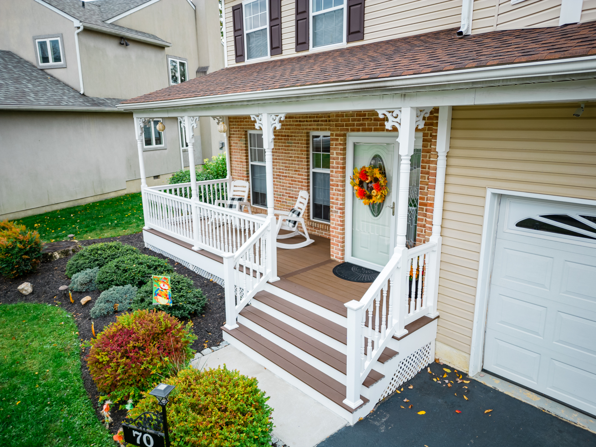 image of a porch with decorative details and lattice skirting in media pa built by integrous fences and decks featuring timbertech decking white vinyl railing and white vinyl with decorative spindles decorative white posts white decorative post to beam brackets and underdeck lattice skirting