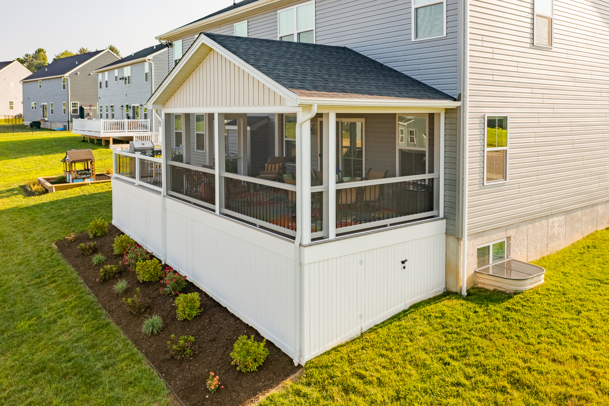 image of a deck with a screened in roof area and vynl deck skirting all built by integrous fences and decks complemented by nice landscaping