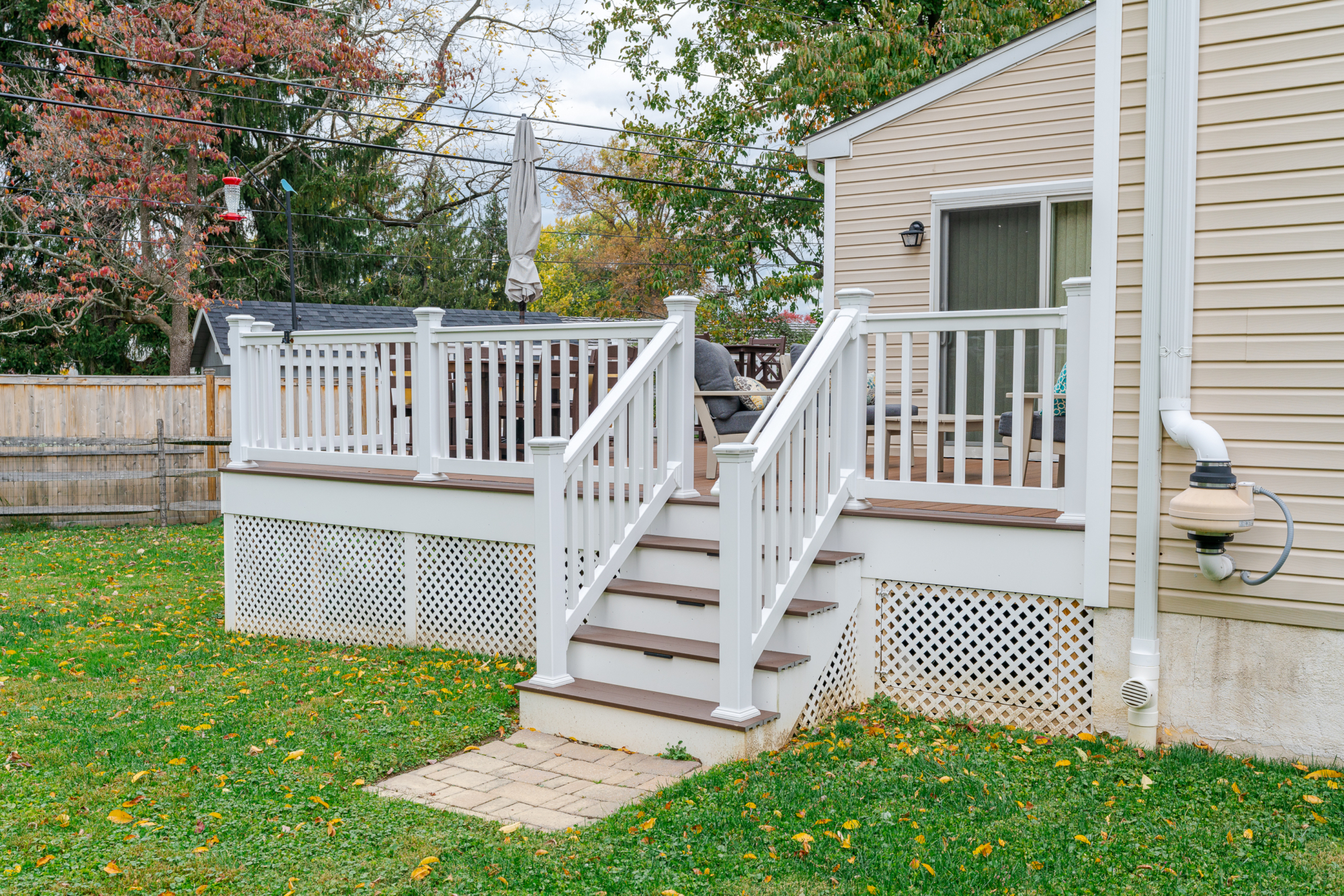 image of a deck with lattice skirting in media pa built by integrous fences and decks featuring timbertech decking white vinyl railing, and white vinyl underdeck lattice skirting with two steps to grade