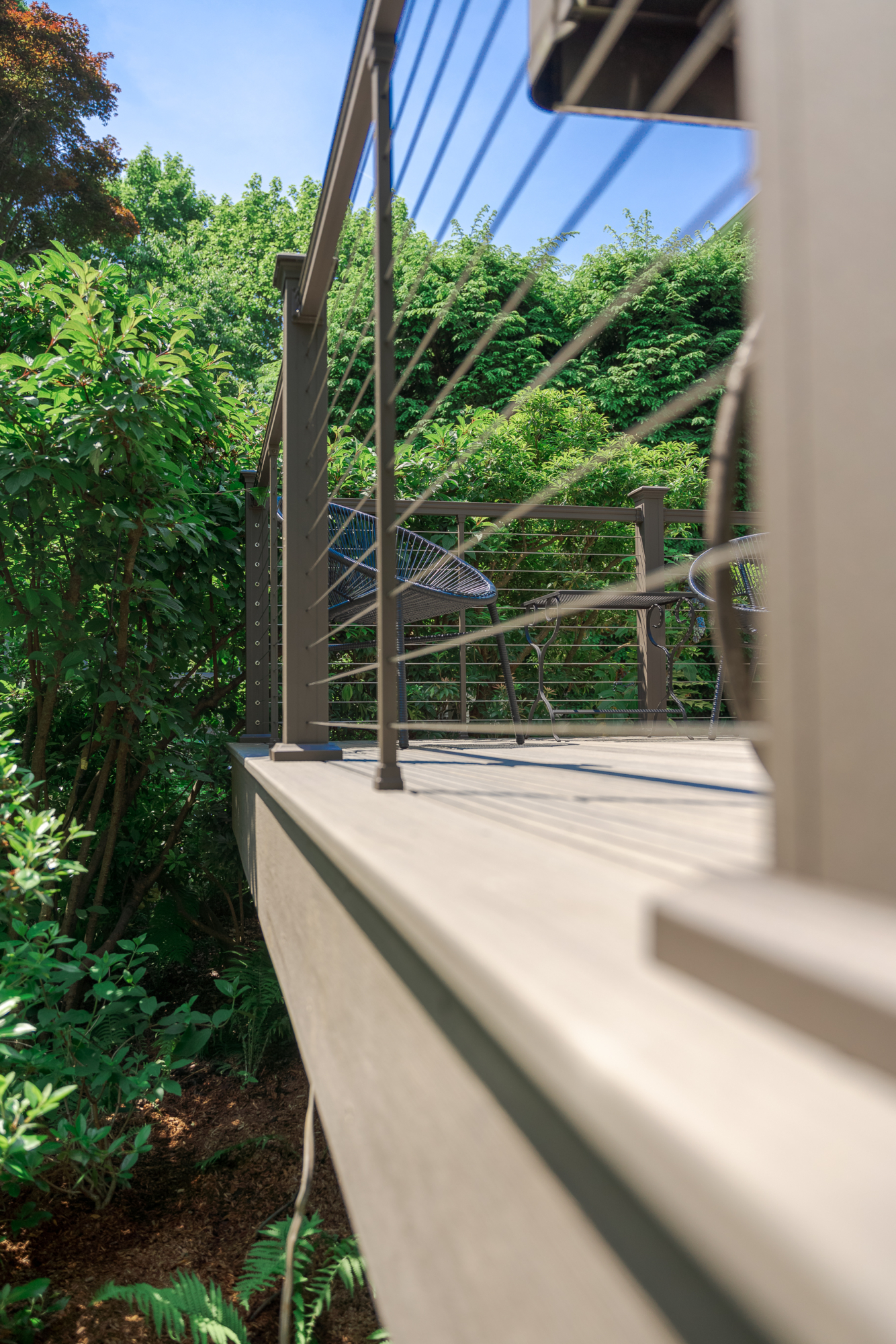 image of a deck in elkins pa built by integrous fences and decks featuring cable railing and timbertech decking located in a beautiful garden backyard