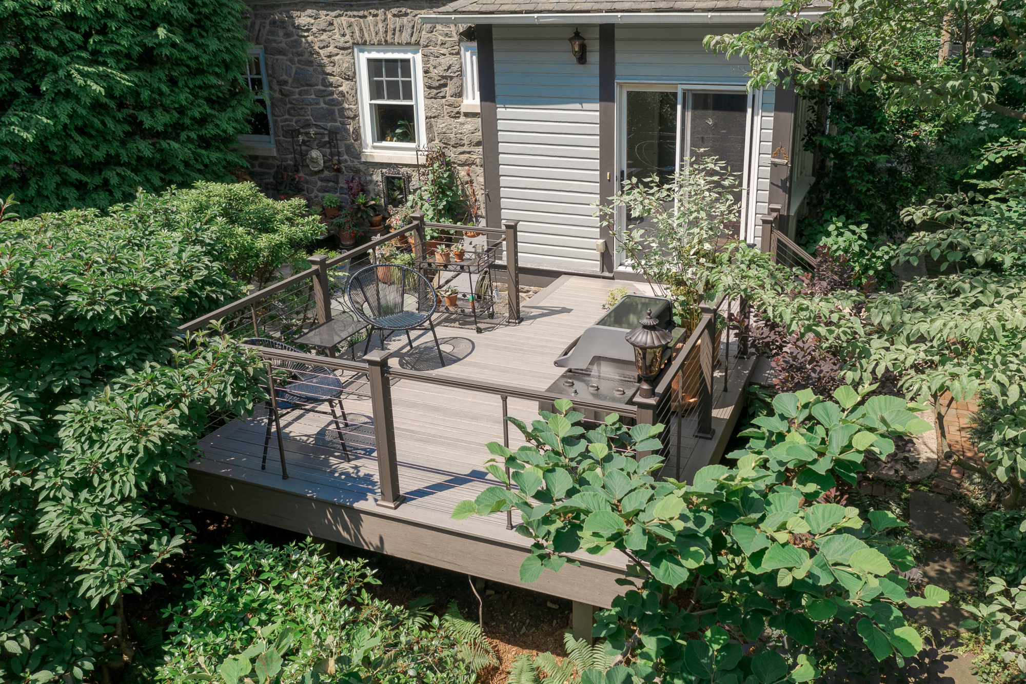 image of a deck in elkins pa built by integrous fences and decks featuring cable railing and timbertech decking located in a beautiful garden backyard