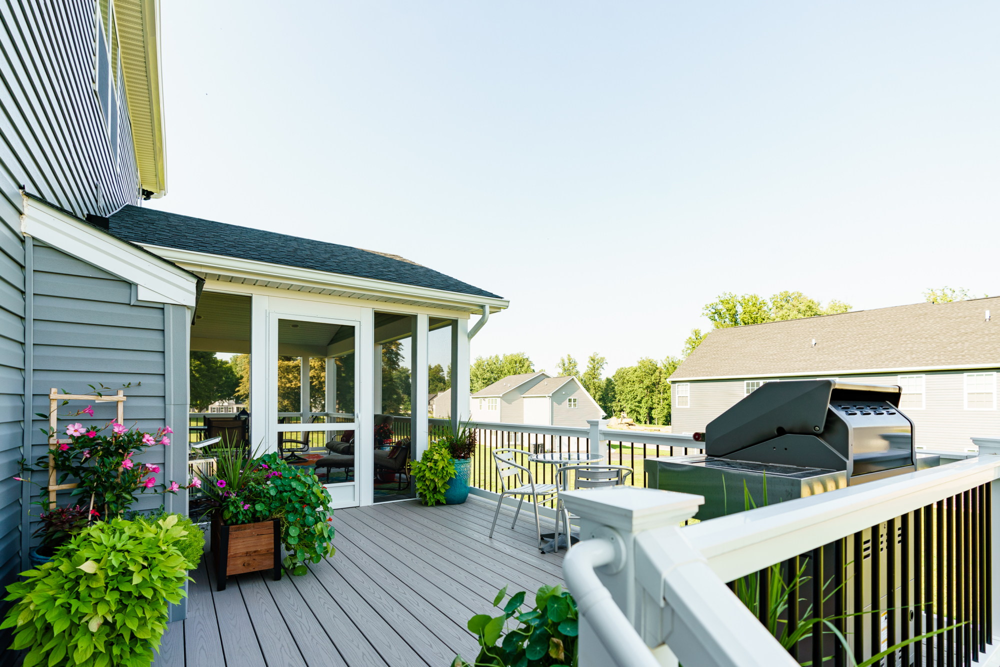 image of a deck with timbertech decking and vynl railing with black aluminum balusters a screened in roof area is also included built by integrous fences and decks