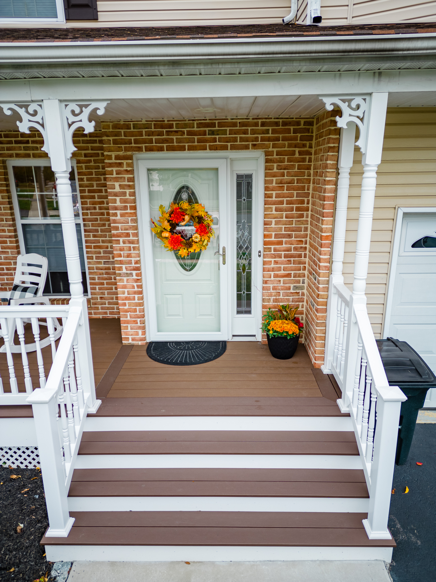 image of a porch with decorative details and lattice skirting in media pa built by integrous fences and decks featuring timbertech decking white vinyl railing and white vinyl with decorative spindles decorative white posts white decorative post to beam brackets and underdeck lattice skirting